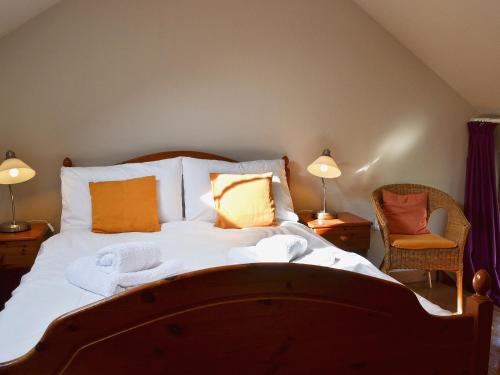 a bedroom with a large bed with two lamps and a chair at TY NANT-oxl in Gwynfe