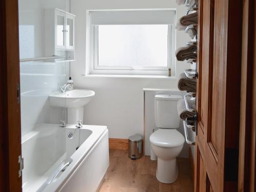 a bathroom with a toilet and a sink and a bath tub at The Paddock in Portmahomack