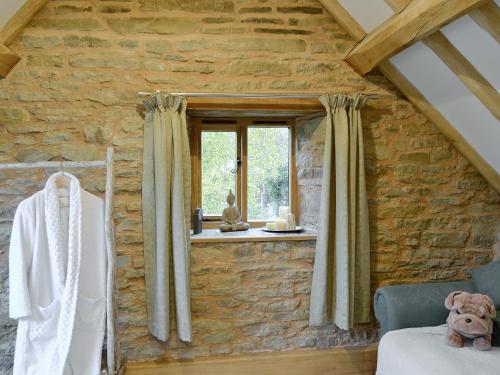 a bedroom with a stone wall and a window at Acorn Cottage in Croft