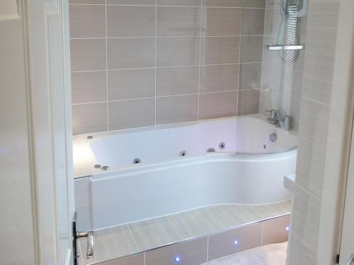 a white bath tub in a bathroom with tiles at 3 Eldin Hall Properties in Cayton