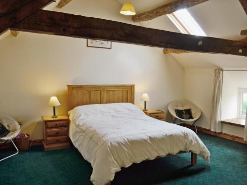 a bedroom with a large bed and two chairs at Dol Afon - Hw7588 in Llanuwchllyn