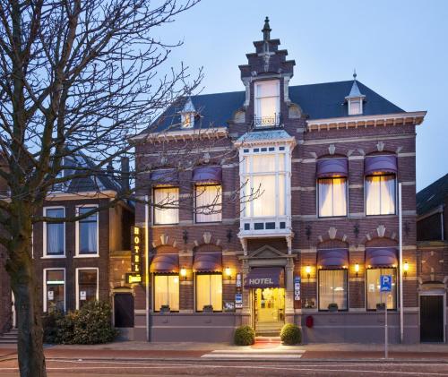 a building on a street with a tree in front at Hotel Dordrecht in Dordrecht
