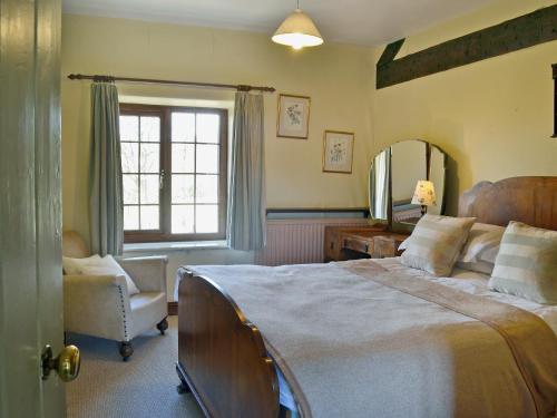 a bedroom with a large bed and a chair at Trowley Farmhouse in Llanbedr