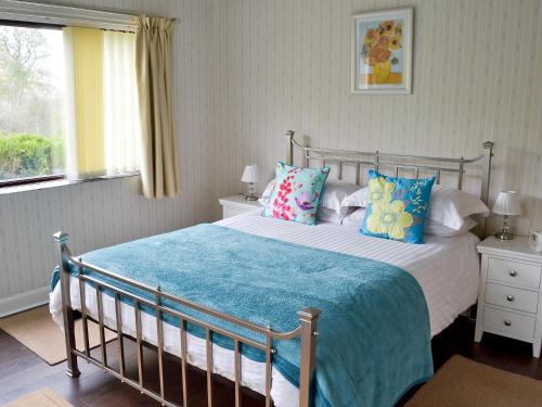 a bedroom with a bed with a blue blanket and pillows at Cobden View in Sabden