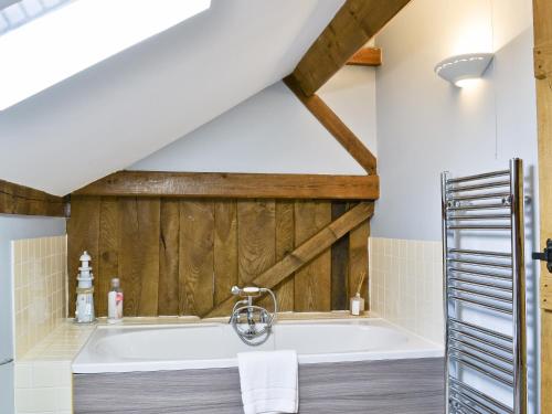 a bath tub in a bathroom with wooden walls at The Granary-e3567 in Uggeshall