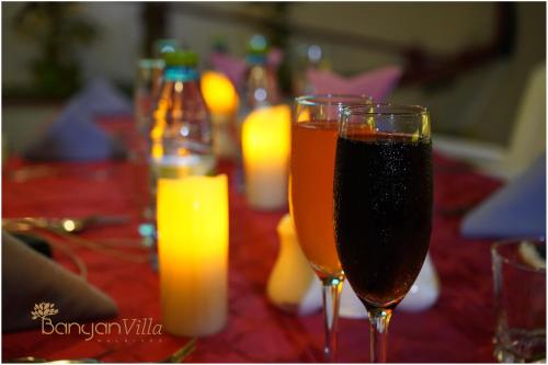 two glasses of wine sitting on a table with drinks at Banyan Villa Maldives Dhangethi in Dhangethi