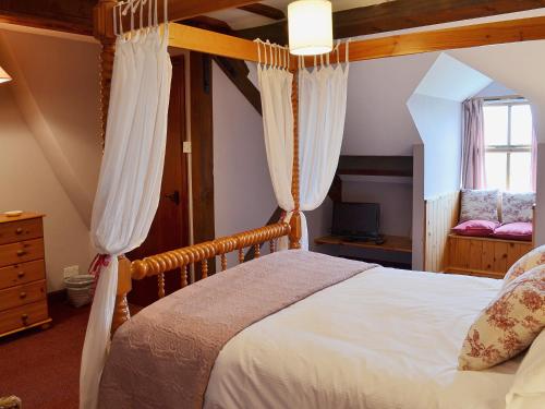 a bedroom with a bed with white sheets and curtains at Rose Cottage II in Scalby