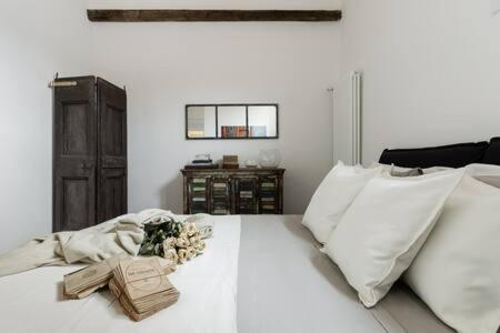een wit bed met witte kussens en bloemen erop bij RED Appartamento immerso tra le mura bolognesi in Bologna