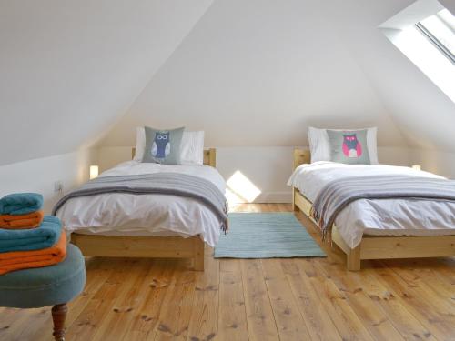 a bedroom with two twin beds and a blue chair at Southlake Barn in Dousland