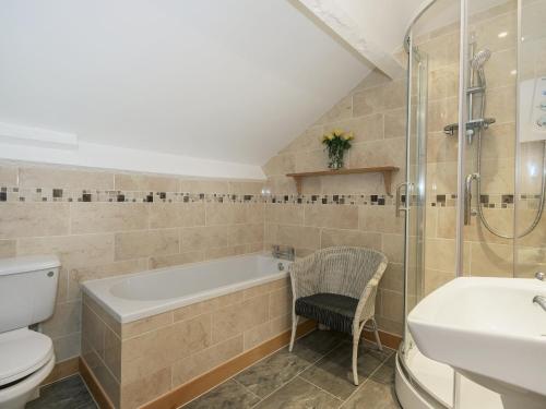 a bathroom with a tub and a toilet and a sink at Hazel Grove House in Beetham