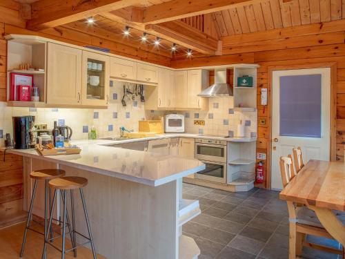 a kitchen with white cabinets and a wooden ceiling at Camelog in Little Petherick