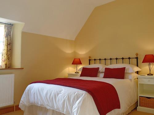 a bedroom with a large bed with red pillows at Lantern Cottage in Longborough