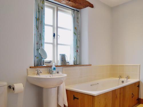 a bathroom with a sink and a tub and a window at Lantern Cottage in Longborough