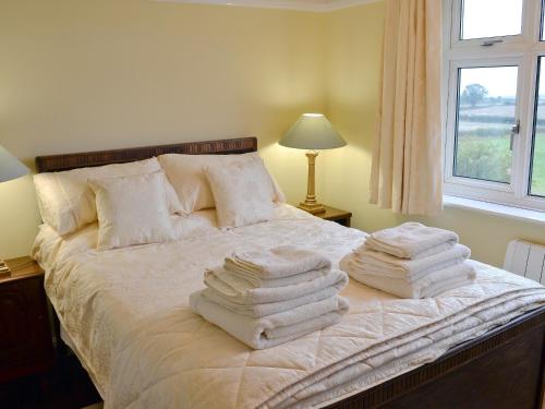 a group of towels stacked on a bed with a window at Bryn Tor - The Gardeners House in Bolsover