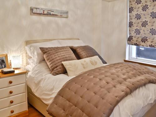 a bed with a large tufted ottoman next to a window at Rockview in Cellardyke