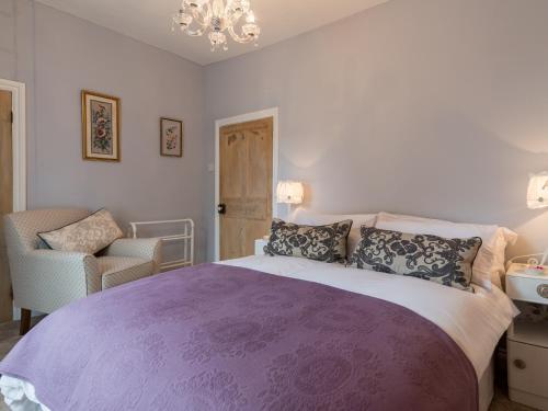 a bedroom with a purple bed and a chandelier at Brewery House Cottage in Bishop Middleham