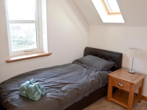 Cama en habitación con 2 ventanas y mesa en Carron House en Lochcarron