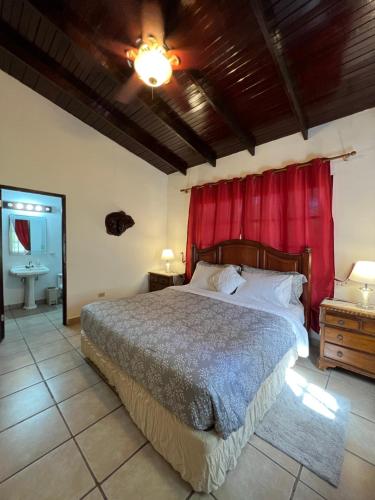 1 dormitorio con 1 cama grande y cortina roja en La Casa de los Patos, en El Valle de Antón