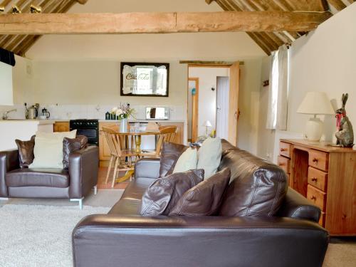 uma sala de estar com um sofá de couro e uma cozinha em The Carthouse em Malmesbury