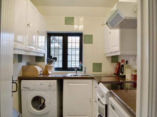 a kitchen with a washing machine and a sink at Violet Cottage in Catfield