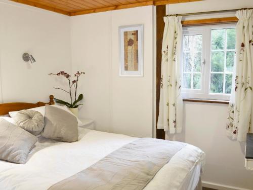 a bedroom with a bed with white sheets and a window at Summer House in St Asaph