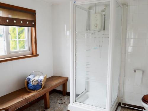 a shower in a bathroom with a wooden bench at Summer House in St Asaph