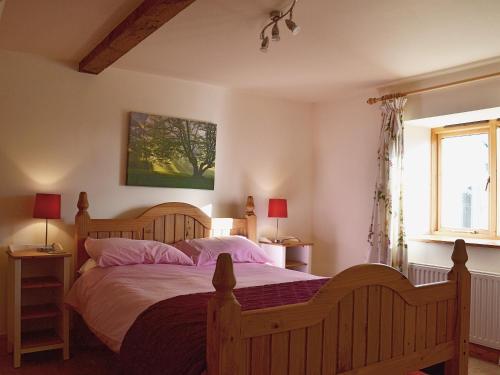a bedroom with a large bed and two windows at Stable Cottage in Oswestry