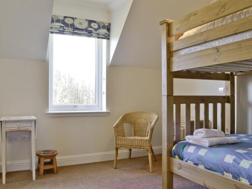 a bedroom with a bunk bed and a chair and a window at Degnish Farmhouse - Swwu in Kilmelfort