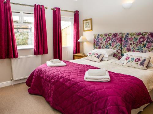 ScalbyにあるTroutbeck Cottageのベッドルーム1室(紫色のベッド1台、タオル付)