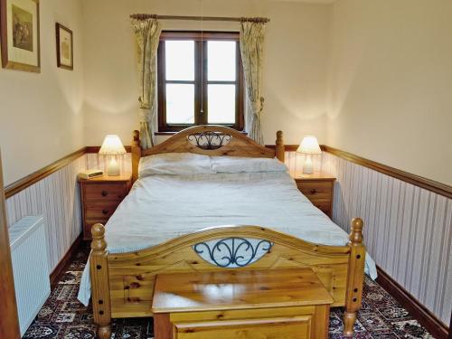 エバーショットにあるWoods Cottageのベッドルーム1室(木製ベッド1台、窓付)