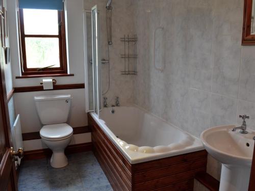 een badkamer met een bad, een toilet en een wastafel bij Woods Cottage in Evershot