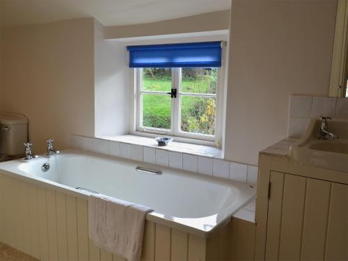uma grande banheira branca na casa de banho com uma janela em Mill House em Rievaulx