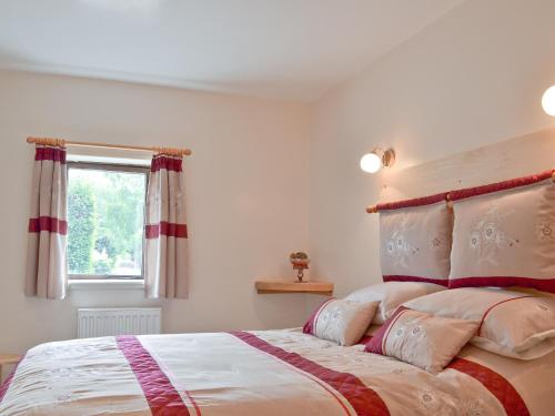 a bedroom with a large bed and a window at Waterfall Cottage in Tansley