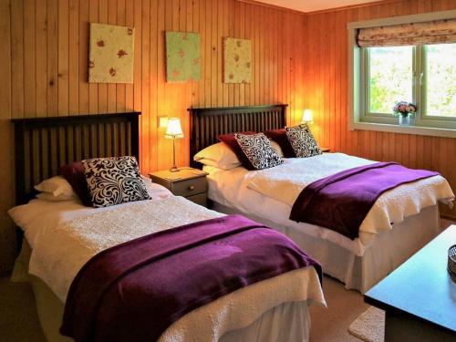 dwa łóżka w pokoju z drewnianymi panelami w obiekcie The Goyle-e4528 w mieście Uplowman