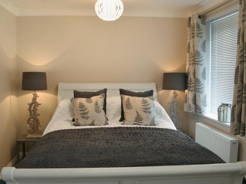 a bedroom with a white bed with pillows and a window at Elm Tree Cottage in Foxholes