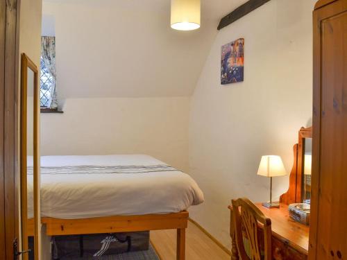 a small bedroom with a bed and a desk at Honeysuckle Cottage in Woolacombe