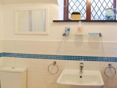a bathroom with a sink and a toilet and a window at Honeysuckle Cottage in Woolacombe