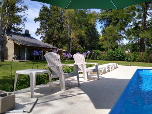 un grupo de sillas blancas sentadas junto a una piscina en Casa Quinta Roen Gral Rodriguez zona oeste en General Rodríguez