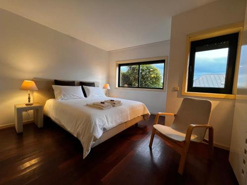 a bedroom with a bed and a chair and a window at Foz Velha House in Porto