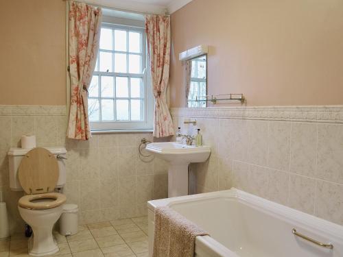 a bathroom with a toilet and a sink and a tub at Laundry Cottage in Uldale