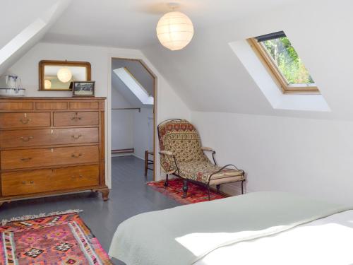 a bedroom with a bed and a dresser and a chair at Malthouse Barn in Hastingleigh