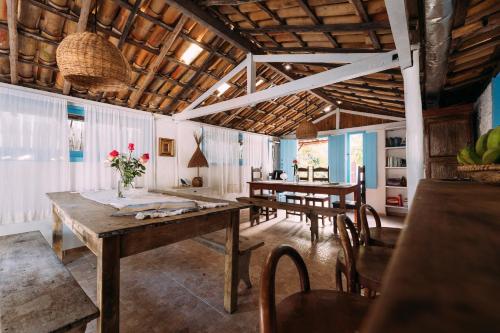 comedor con mesas y sillas de madera en Vila Luz, en Caraíva