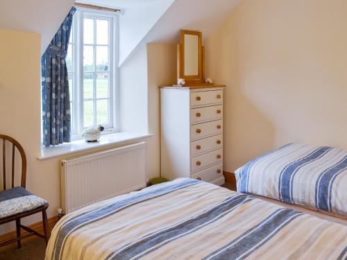 a bedroom with two beds and a window and a dresser at Gunluk Cottage in Brompton