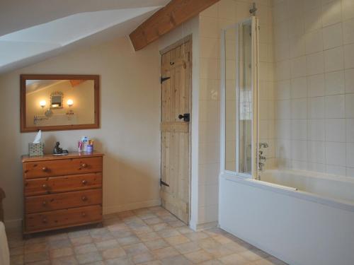 a bathroom with a shower and a dresser with a mirror at Gunluk Cottage in Brompton