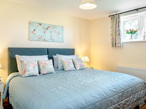 Un dormitorio con una cama azul con almohadas y una ventana en Blackberry Cottage, en North Hill