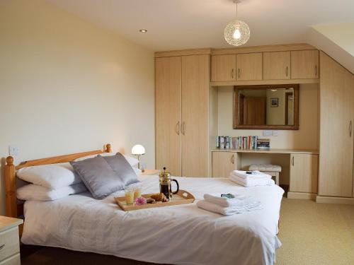 a bedroom with a bed with a tray of food on it at Brynymor Cottage in Llangennith