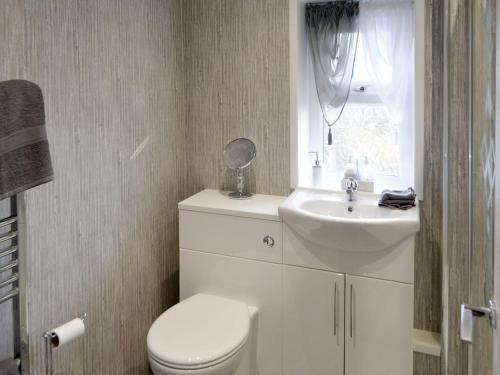 a bathroom with a toilet and a sink and a window at Seashells By The Sea in Newbiggin-by-the-Sea