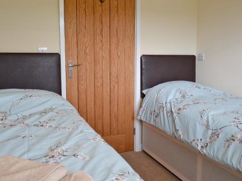 a bedroom with two beds and a wooden door at Y Gorlan in Llanllechid