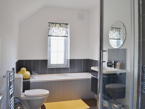 a bathroom with a tub and a toilet and a sink at One Parkhayes in Woodbury
