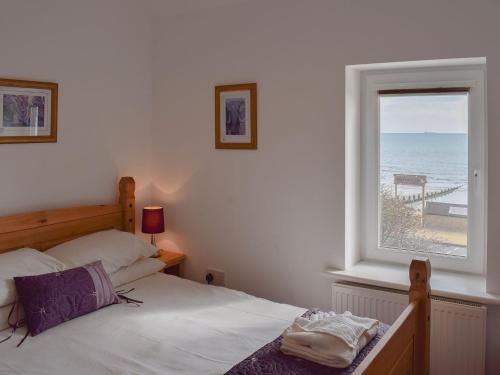 a bedroom with a bed and a window with the ocean at Little Lismoy in Sandown